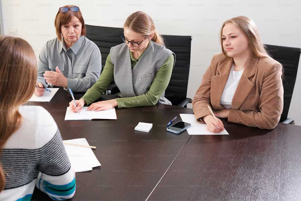 A group of women participating in an employment law training session, sitting around a conference table, taking notes and discussing workplace policies and legal guidelines.