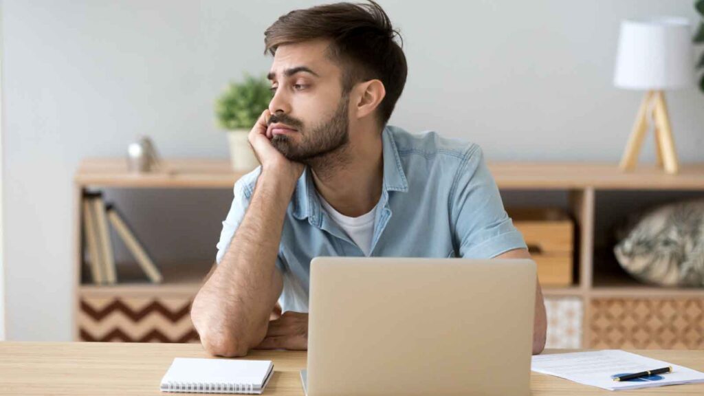 A man appears disengaged while participating in a virtual training session on his laptop.