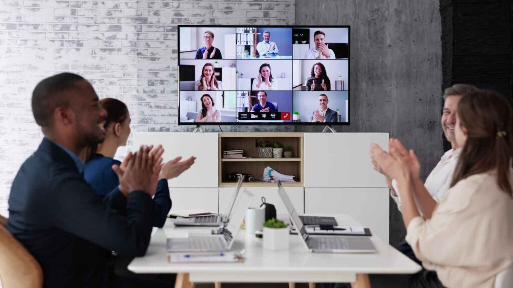 HR professionals leading a seminar in a small conference room, with participants clapping in appreciation.